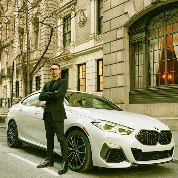 Image of Caption: Christian Siriano posed in front of his white BMW